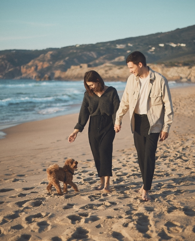 Casal feliz com cachorro na praia